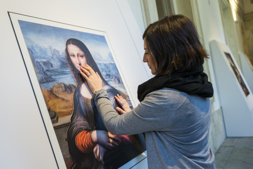 A visitor to the exhibition touches an augmented images of “La Gioconda,” believed to have been painted by an apprentice of Leonardo.